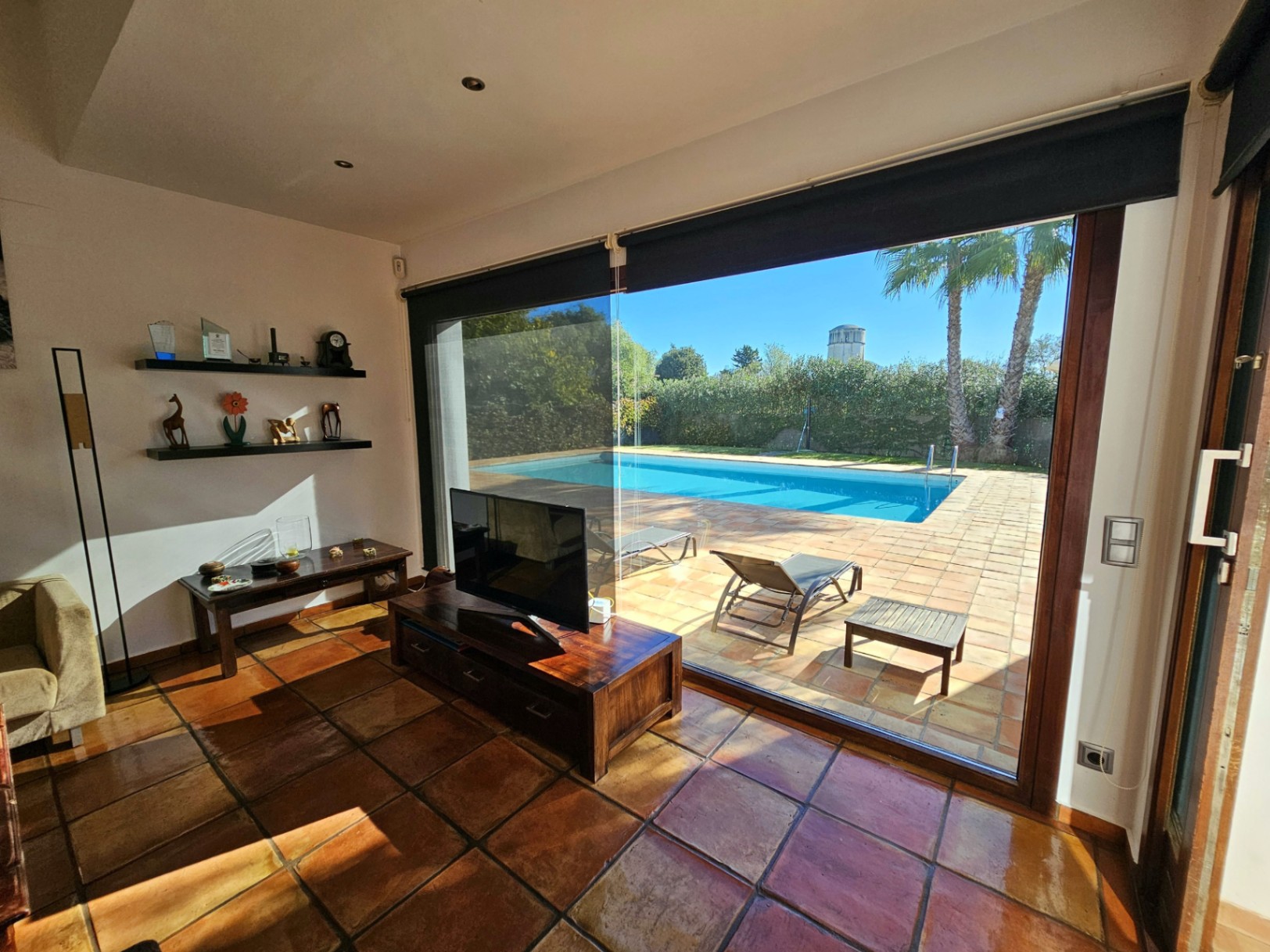 Living space with handmade clay tile flooring and floor-to-ceiling glass doors providing direct access to the pool and sun terrace.