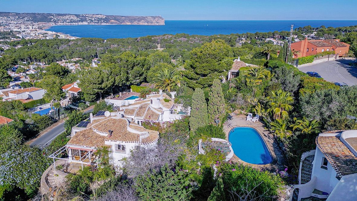Aerial view of the Portichol property featuring terracotta roofs, solar panels, a private pool, and panoramic views of Javea bay and the Mediterranean Sea.