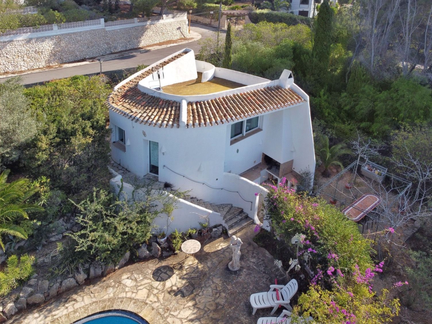 Aerial view of the secondary villa featuring traditional Mediterranean architecture, terracotta tile roofing, an outdoor BBQ area, and stone-paved terraces.