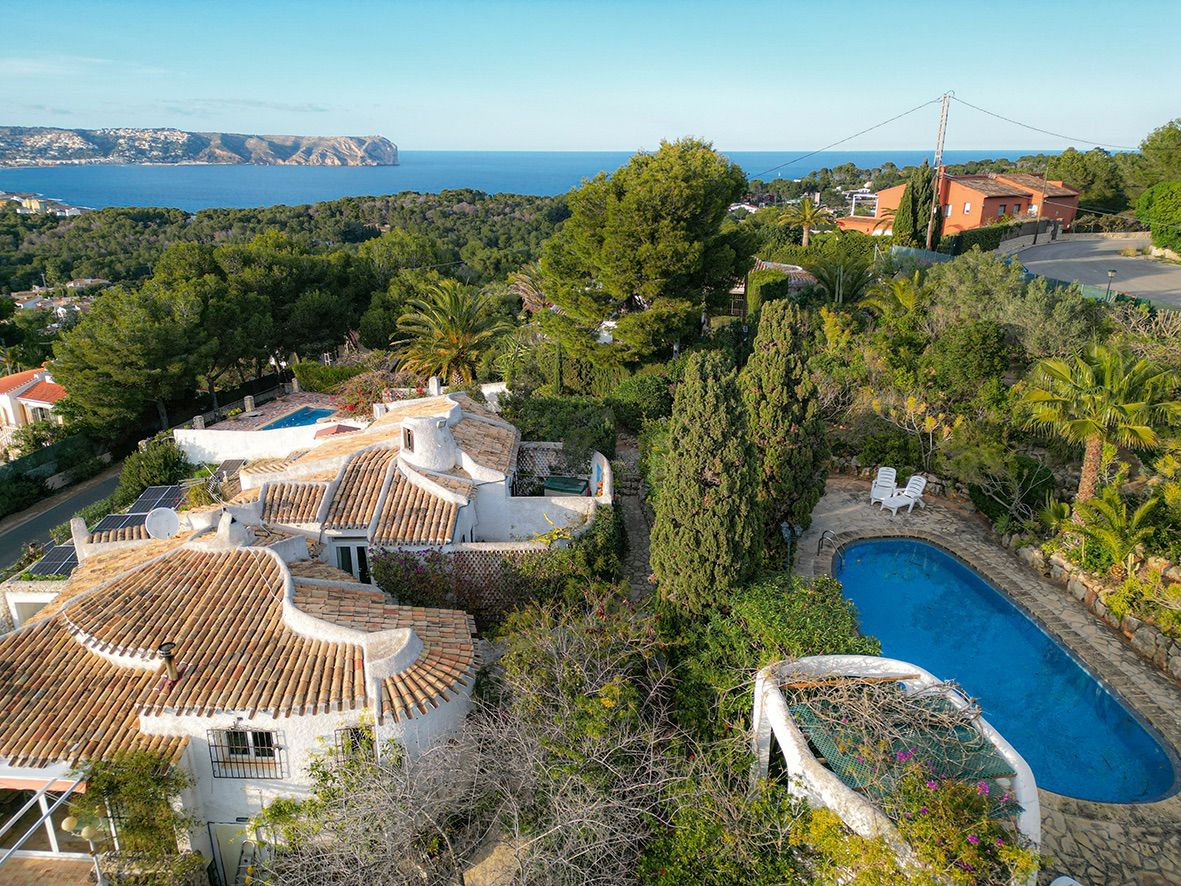 Elevated view of the traditional villa featuring terracotta roofs, a kidney-shaped pool, and expansive views of the Mediterranean Sea.