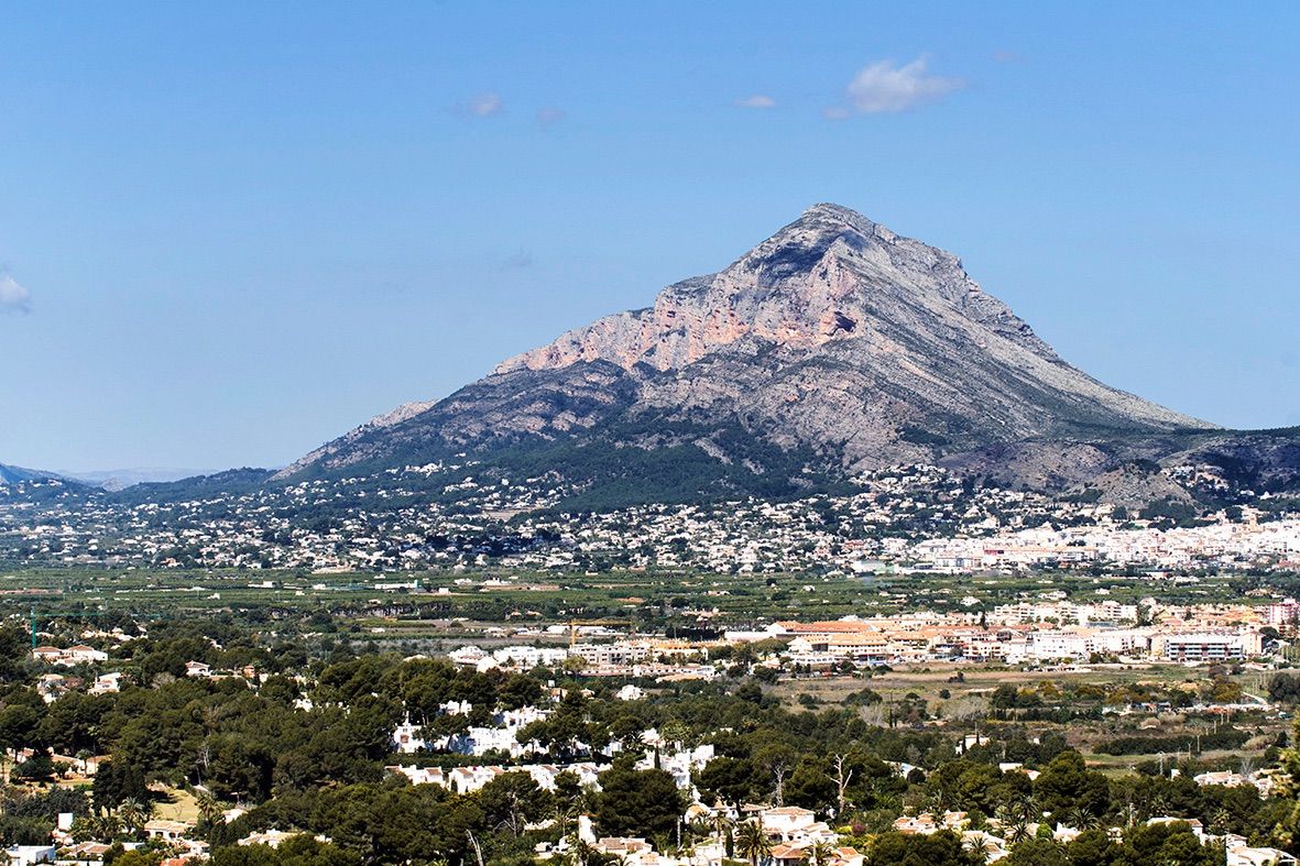 Panoramic views of the Montgó mountain and the Jávea valley, showcasing the Mediterranean landscape and surrounding residential areas under a clear sky.