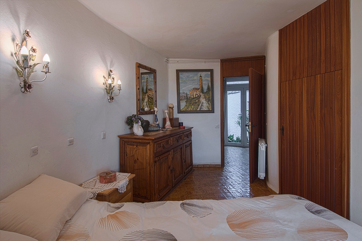 Rustic bedroom featuring built-in wood wardrobes, tiled flooring, and decorative wall sconces providing warm ambient lighting.