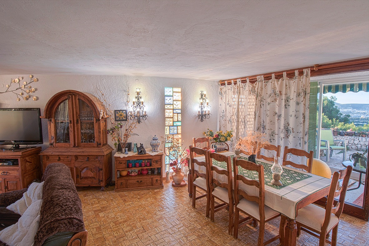 Rustic dining area featuring traditional wooden furniture, tiled flooring, and large sliding doors opening onto a terrace with scenic valley views.