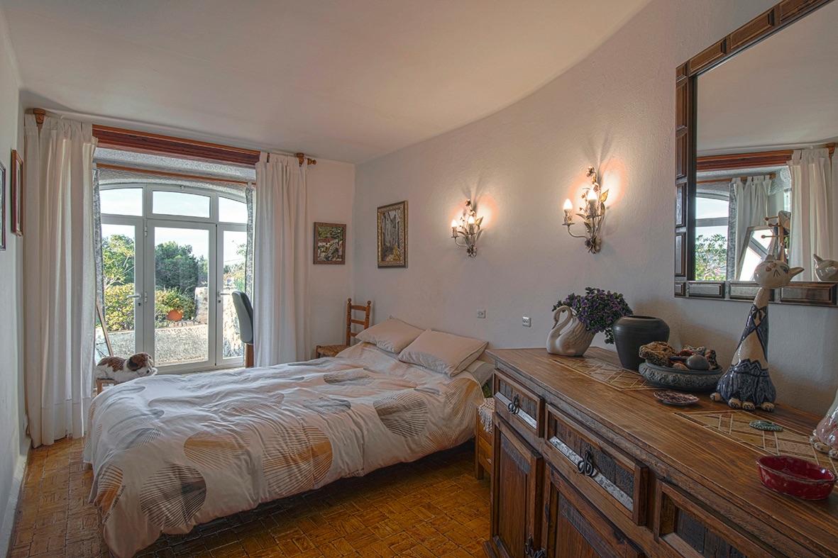 Traditional bedroom featuring terracotta tile flooring, rustic wooden furniture, and arched glass doors providing direct access to the garden.