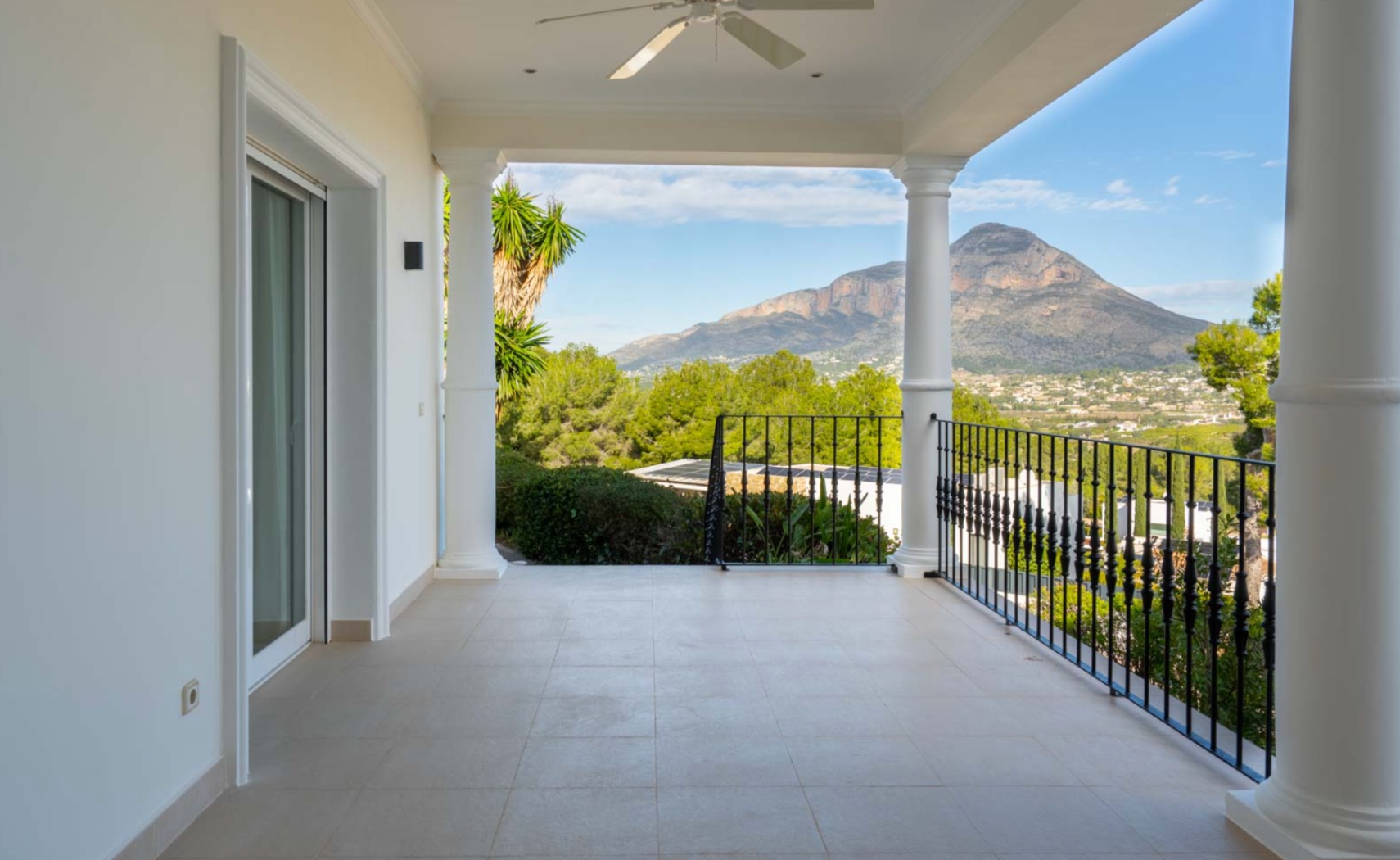 Covered terrace featuring classical columns and tiled flooring, providing panoramic views of the Montgó mountain and the surrounding valley.